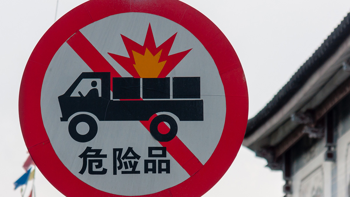 Уличный знак с перечеркнутым грузовиком и надписью на китайском языке