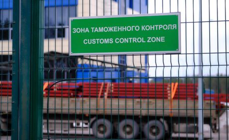 Зеленая табличка на решетке с надписью на русском и английском Зона таможенного контроля